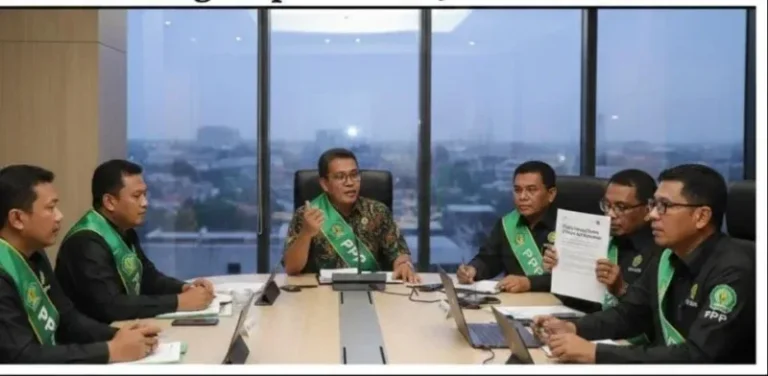 Sekelompok pria mengenakan seragam hijau khas PPP sedang melakukan rapat formal di sebuah ruang pertemuan modern. Salah satu peserta menunjukkan dokumen usulan, dengan latar belakang jendela besar yang menampilkan pemandangan kota di sore hari. Di bagian atas terdapat teks judul berita mengenai usulan penghapusan jabatan Kadus oleh PAC PPP Pegandon.
