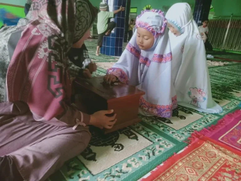 Siswa PAUD Purnama Desa Getas memasukkan sedekah ke kotak amal Masjid Al Barokah Dusun Genting setelah melaksanakan salat sunnah Dhuha bersama.